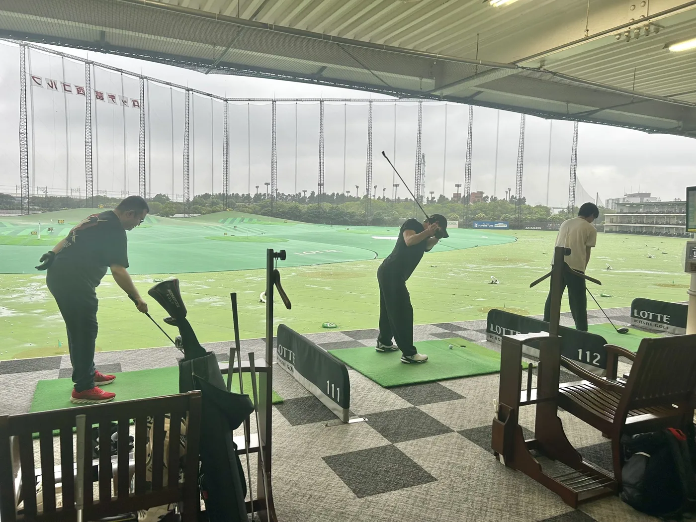 休日にゴルフ練習場で打ちっぱなしをするメンバー